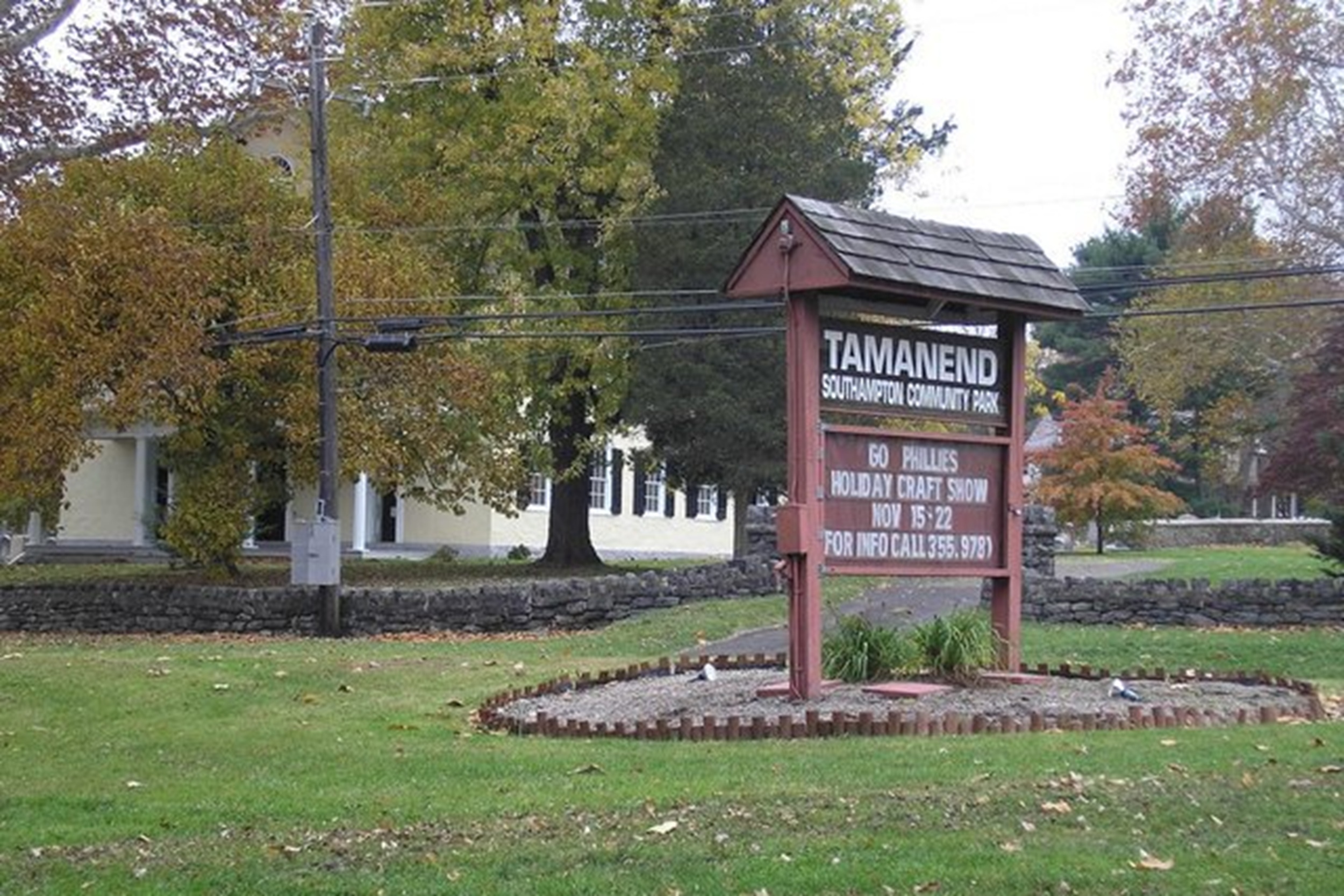 Entrance sign for Tamanend Southampton Community Park with trees behind and a low stone wall nearby.